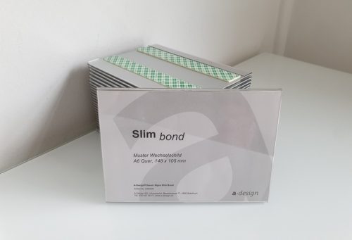 Schild Slim Bond mit beispielhaftem Papiereinzug und Stapel von Schilder im Hintergrund.