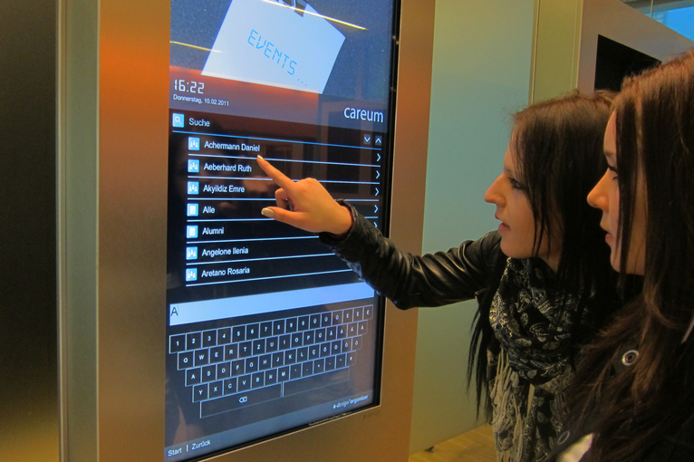 Zwei Schülerinnen bedienen auf einer A-Design Stele die Personensuche über die A-Design Organizer - Software